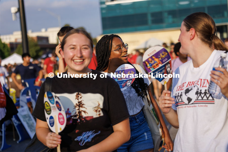 Laila Doyle, a sophomore from Edmond, Oklahoma, center, keeps cool with her friends thanks to a Lied Center fan. Big Red Welcome Street Fest on the Memorial Stadium loop. Hundreds of clubs and organizations give away stuff to students. August 20, 2023. Photo by Craig Chandler / University Communication.