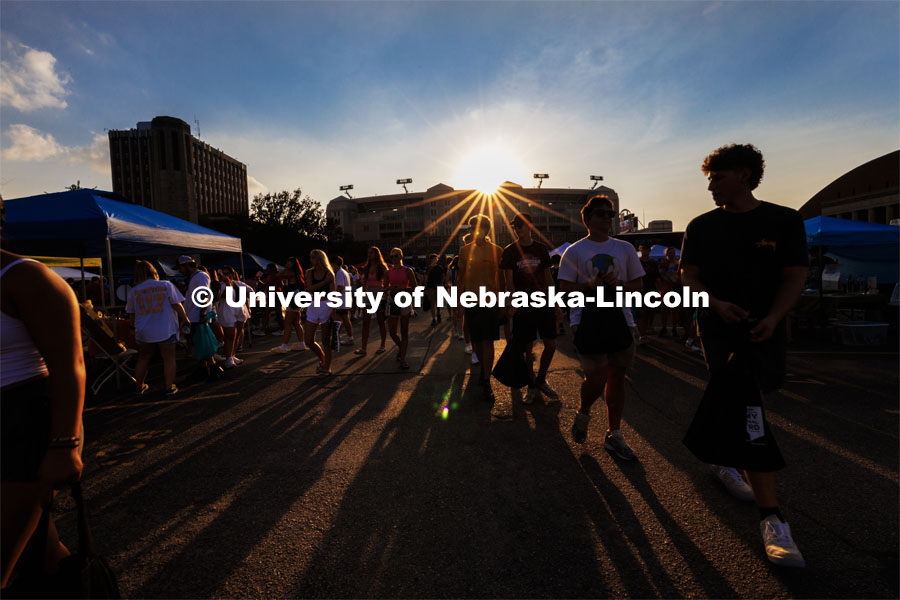 The sun sets over Memorial Stadium during the Big Red Welcome Street Fest on the Memorial Stadium loop. Hundreds of clubs and organizations give away stuff to students. August 20, 2023. Photo by Craig Chandler / University Communication.