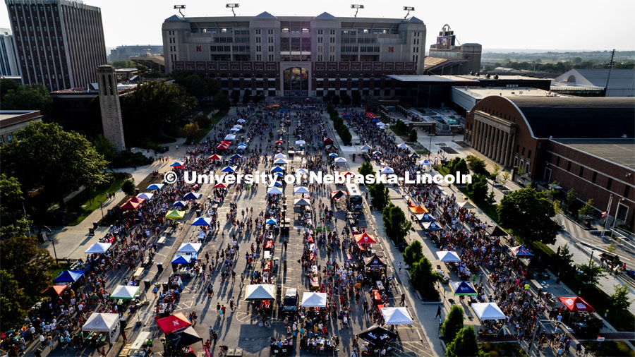 Aerial view of students and their Sunday evening shadows stroll the aisles at the Big Red Welcome Street Fest on the Memorial Stadium loop. Hundreds of clubs and organizations give away stuff to students. August 20, 2023. Photo by Craig Chandler / University Communication.