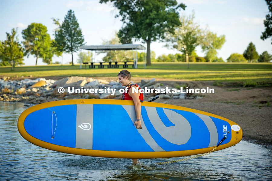 A student carrys their paddleboard into the water at Branched Oak Lake. About Lincoln - Paddleboarding at Branched Oak Lake with Campus Rec. September 13, 2023. Photo by Kristen Labadie / University Communication.