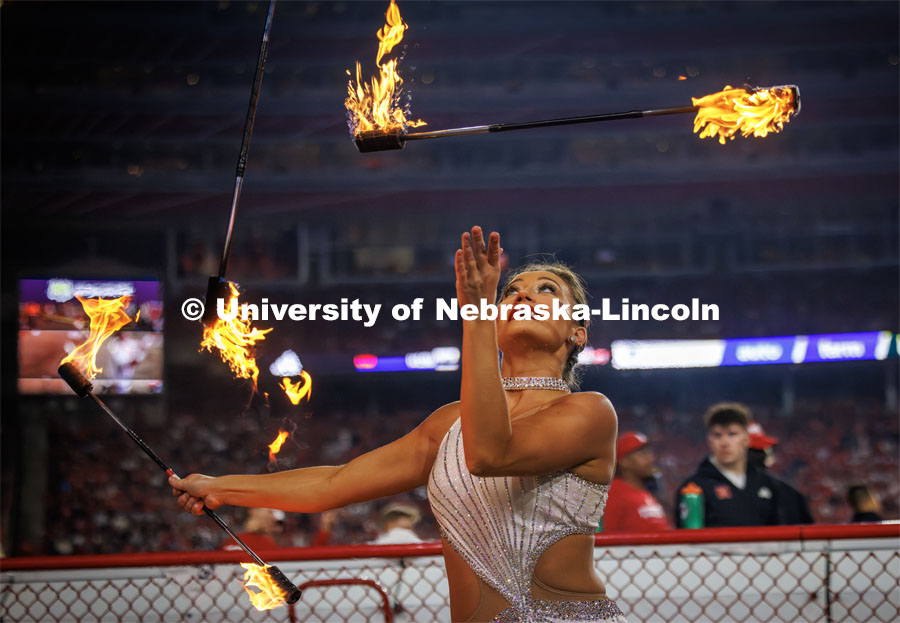 Steffany Lien of Lincoln twirls flaming batons on the sideline next to the Cornhusker Marching Band. Northern Illinois football in Memorial Stadium. September 16, 2023. Photo by Craig Chandler / University Communication.