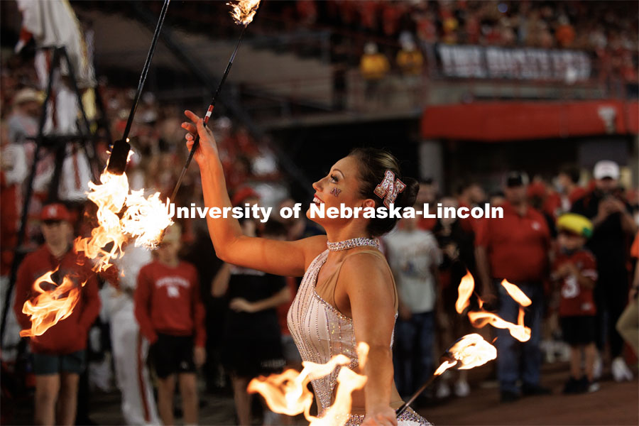 Steffany Lien of Lincoln twirls flaming batons on the sideline next to the Cornhusker Marching Band. Northern Illinois football in Memorial Stadium. September 16, 2023. Photo by Craig Chandler / University Communication.