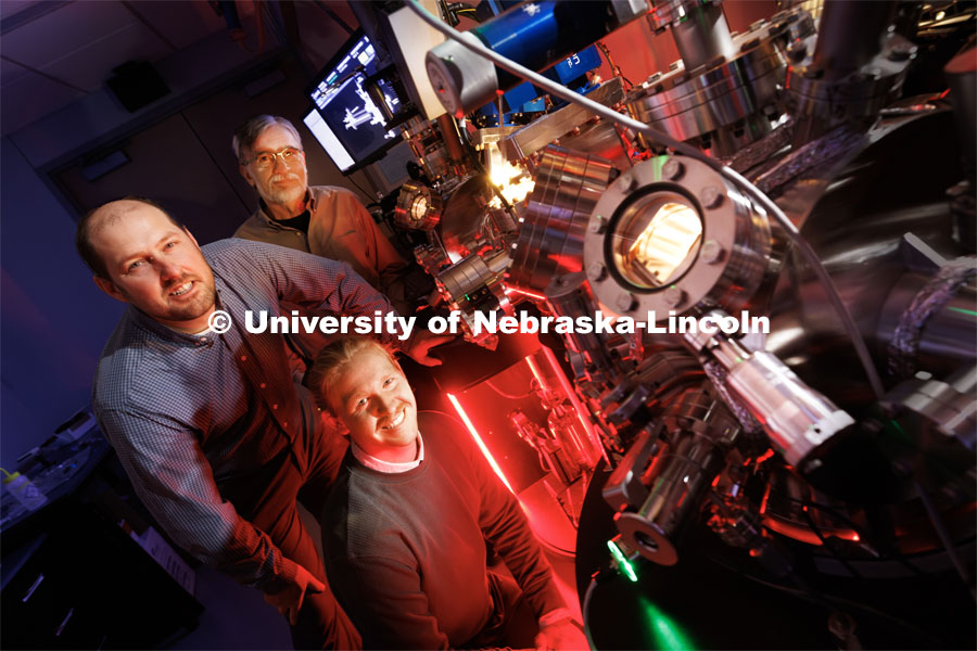 Craig Zuhlke (left), Associate Professor of Electrical and Computer Engineering; George Gogos (back), Wilmer J. and Sally L. Hergenrader Professor of Mechanical and Materials Engineering; and Graham Kaufman (front), doctoral student in electrical engineering, pose with the now active Leybold ultra-high vacuum laser surface processing and materials analysis system in the Engineering Research Center. Zuhlke and Gogos are co-directors of the Center for Electro-Optics and Functionalized Surfaces. October 10, 2023. Photo by Craig Chandler / University Communication.