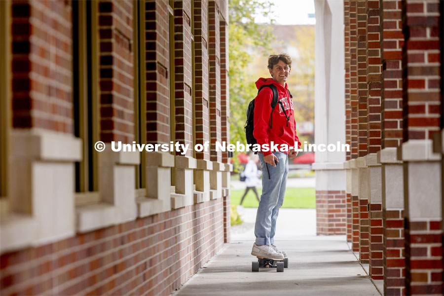 Raikes student skateboarding through the outdoor corridors of the Kauffman Academic Residential Center on their way to class. Raikes School photo shoot. October 18, 2023. Photo by Craig Chandler / University Communication.