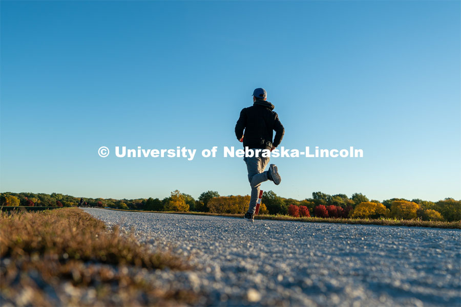 A jogger runs the walking path at Holmes Lake. About Lincoln at Holmes Lake. October 20, 2023. Photo by Matthew Strasburger / University Communication.