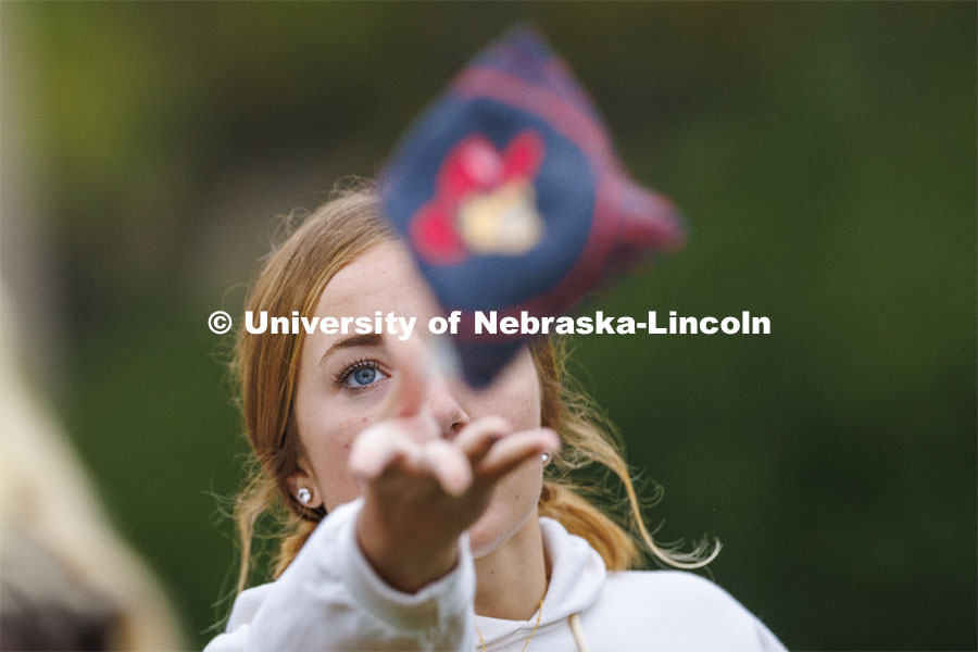 Sadie Larkins, who was competing for the Newman Center, lets a bag fly during Homecoming Cornhole Tournament in the greenspace by the Nebraska Union. October 25, 2023. Photo by Craig Chandler / University Communication.