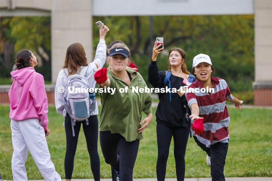 Nghi Ho, right, and Mackenzie Noble practice before the tournament begins as their friends record the action and themselves. The two were competing for Alpha Xi Delta. Cornhole Tournament in the greenspace by the Nebraska Union. October 25, 2023. Photo by Craig Chandler / University Communication.