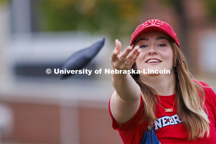Evi Schock throws a bag as she competes for Alpha Omicron Pi Cornhole Tournament for Homecoming in the greenspace by the Nebraska Union. October 25, 2023. Photo by Craig Chandler / University Communication.