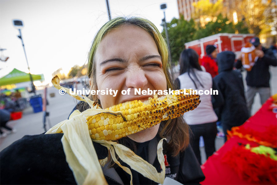 Lani Bohmont digs into an ear of roasted corn at Cornstock. Homecoming parade and Cornstock. October 27, 2023. Photo by Craig Chandler / University Communication.