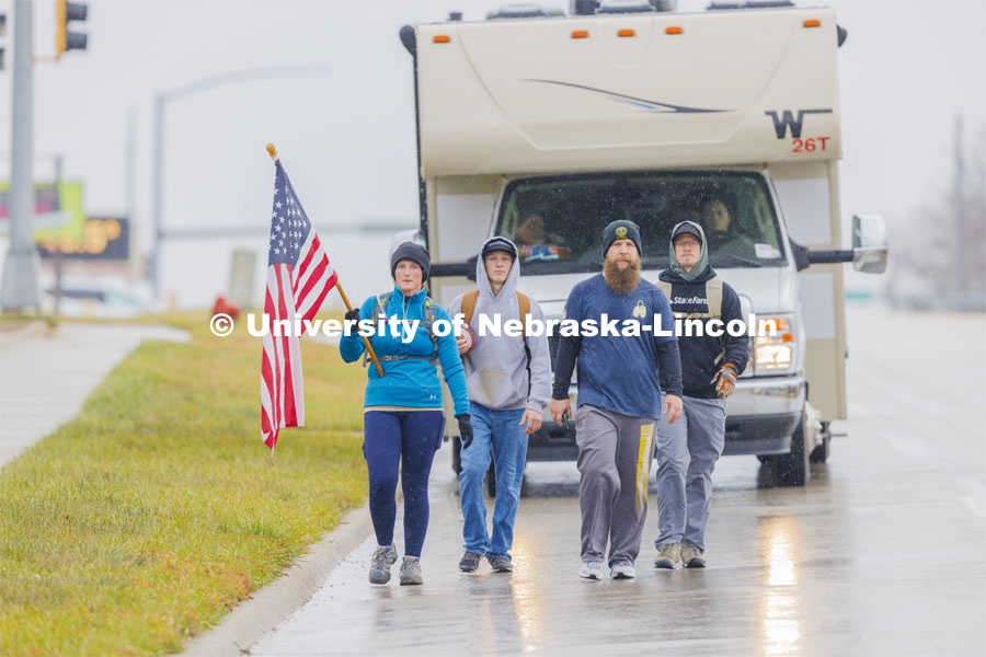 Iowa veterans walking the second day of the Ruck March walk along Hwy 83 east of Atlantic, Iowa, carrying the Nebraska v. Iowa game ball. The Things They Carry" ruck march involving military and veteran students from Iowa and Nebraska. To raise awareness about veteran suicide, through the week, the students walk in 20-mile shifts carrying 20-pound backpacks to commemorate the estimated 20 veterans who die by suicide each day. November 20, 2023. Photo by Craig Chandler / University Communication and Marketing.