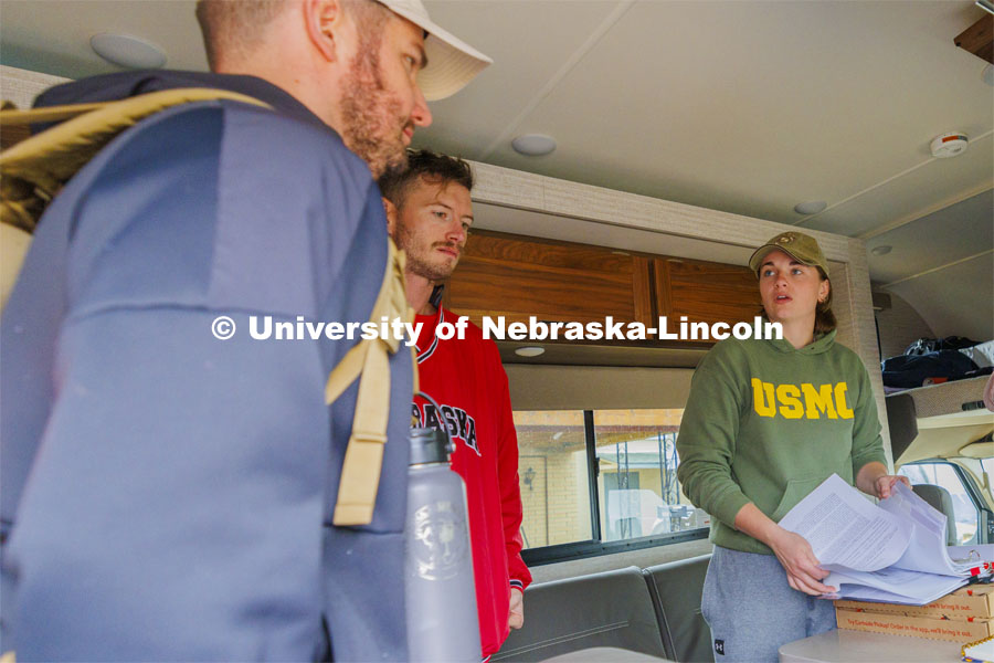 Jenalee Wimer, a senior Animal Science Pre-Veterinary Medicine student and Marine, helps Lincoln veterans (left) Pete Lass and McCain Vesa at the start of sign their wavers for the Monday afternoon session of the march. Ruck Marchers walk along Hwy 83 east of Atlantic, Iowa, carrying the Nebraska v. Iowa game ball. The Things They Carry" ruck march involving military and veteran students from Iowa and Nebraska. To raise awareness about veteran suicide, through the week, the students walk in 20-mile shifts carrying 20-pound backpacks to commemorate the estimated 20 veterans who die by suicide each day. November 20, 2023. Photo by Craig Chandler / University Communication and Marketing.