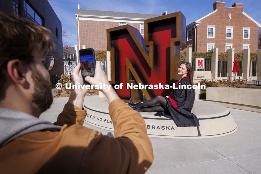Madison Kindig, a graduating senior in psychology from Olathe, Kansas, has her graduation photos taken by friends outside the Nebraska Union and the N sculpture by the Alumni Association. November 22, 2023. Photo by Craig Chandler / University Communication and Marketing.