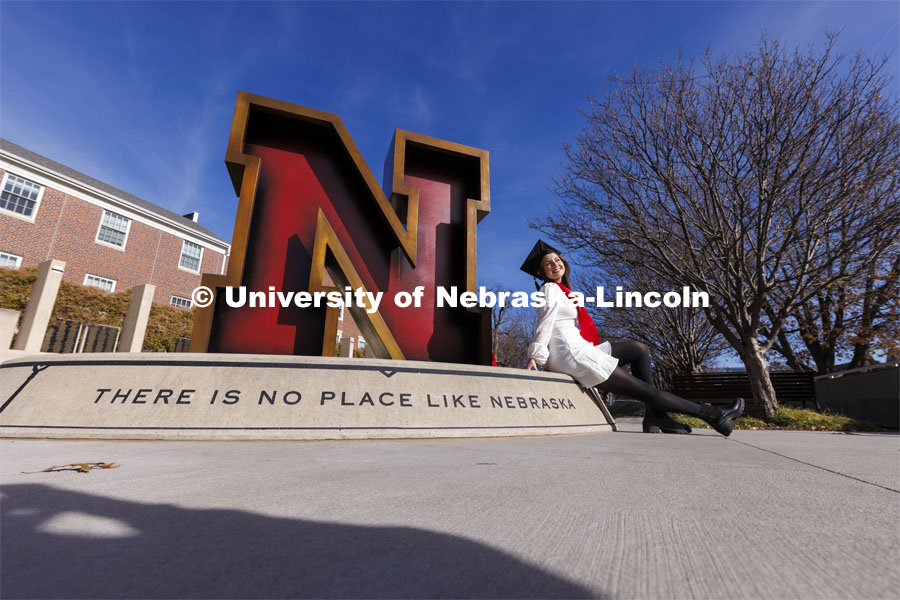 Madison Kindig, a graduating senior in psychology from Olathe, Kansas, has her graduation photos taken by friends outside the Nebraska Union and the N sculpture by the Alumni Association. November 22, 2023. Photo by Craig Chandler / University Communication and Marketing.