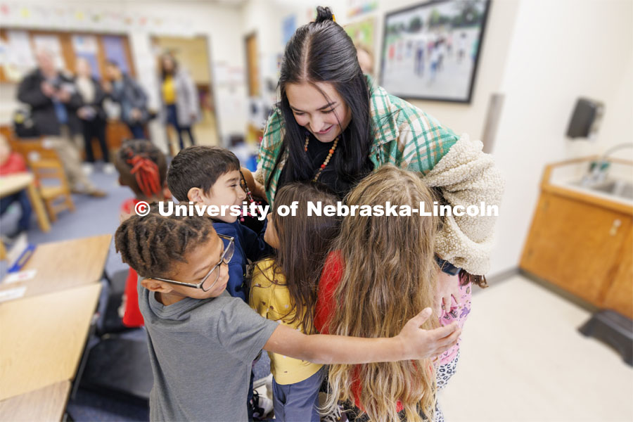 Crandall Blake receives a massive hug from several students when she returned to her classroom for one last time. Blake student taught her kindergarten class at Lakeview Elementary. She had her students sign a pair of white high-top shoes which she will wear at commencement so “her entire class can walk across stage with her”. December 13, 2023. Photo by Craig Chandler / University Communication and Marketing.