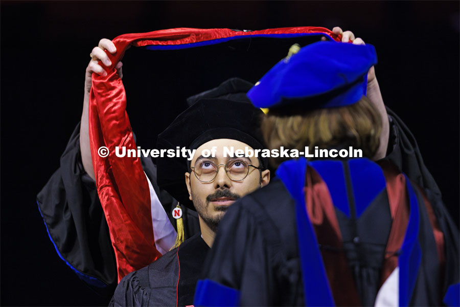 Mohammad Ali Takallou watches as his doctoral hood is lowered over his head. Graduate Commencement at Pinnacle Bank Arena. December 15, 2023. Photo by Craig Chandler / University Communication and Marketing.