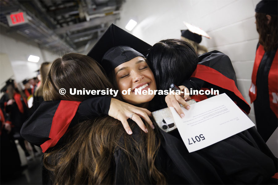 Allie Christensen has a final hug for a couple friends as they lined up before the ceremony. Winter undergraduate commencement in Pinnacle Bank Arena. December 16, 2023. Photo by Craig Chandler / University Communication and Marketing.