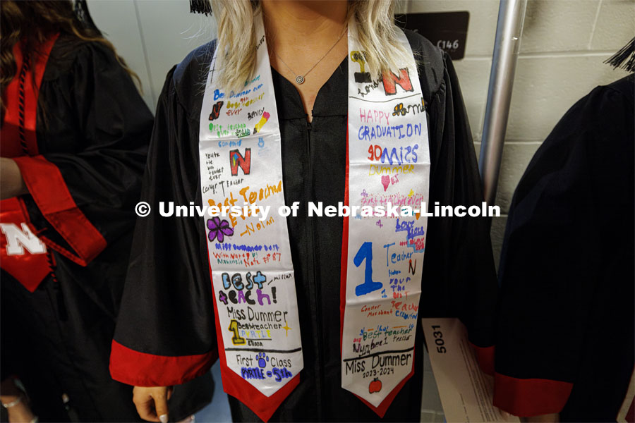 Paxtyn Dummer wears a special sash signed by her students she student taught during the semester. Winter undergraduate commencement in Pinnacle Bank Arena. December 16, 2023. Photo by Craig Chandler / University Communication and Marketing.