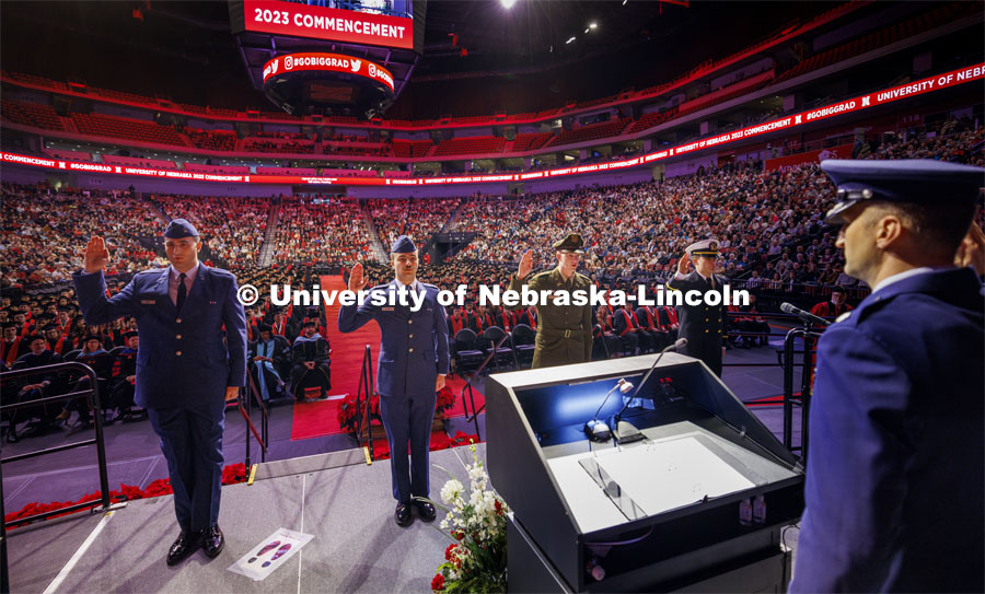Nebraska ROTC candidates for commission repeat their oath on stage given by Lt Col Philip Garito. From left are Hunter Bode and Kale Ensser (Air Force), David Toland (Army) and Dash Spears (Navy). Winter undergraduate commencement in Pinnacle Bank Arena. December 16, 2023. Photo by Craig Chandler / University Communication and Marketing.