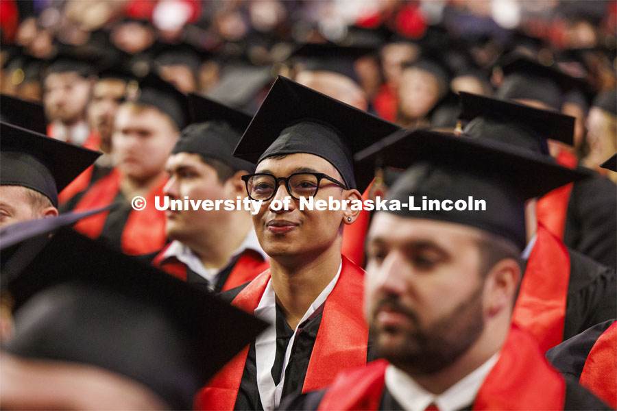 Zoyace Shrestha listens to speakers while awaiting his Engineering degree. Winter undergraduate commencement in Pinnacle Bank Arena. December 16, 2023. Photo by Craig Chandler / University Communication and Marketing.