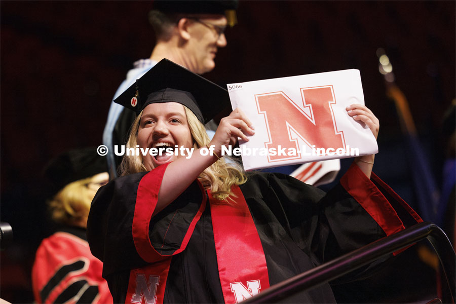 Kayla Klinkacek shows her CEHS diploma to family and friends. Winter undergraduate commencement in Pinnacle Bank Arena. December 16, 2023. Photo by Craig Chandler / University Communication and Marketing.