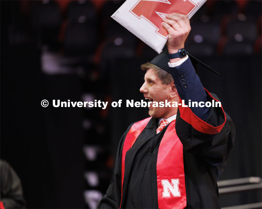 Jacob Madsen shows his CEHS diploma to family and friends. Winter undergraduate commencement in Pinnacle Bank Arena. December 16, 2023. Photo by Craig Chandler / University Communication and Marketing.