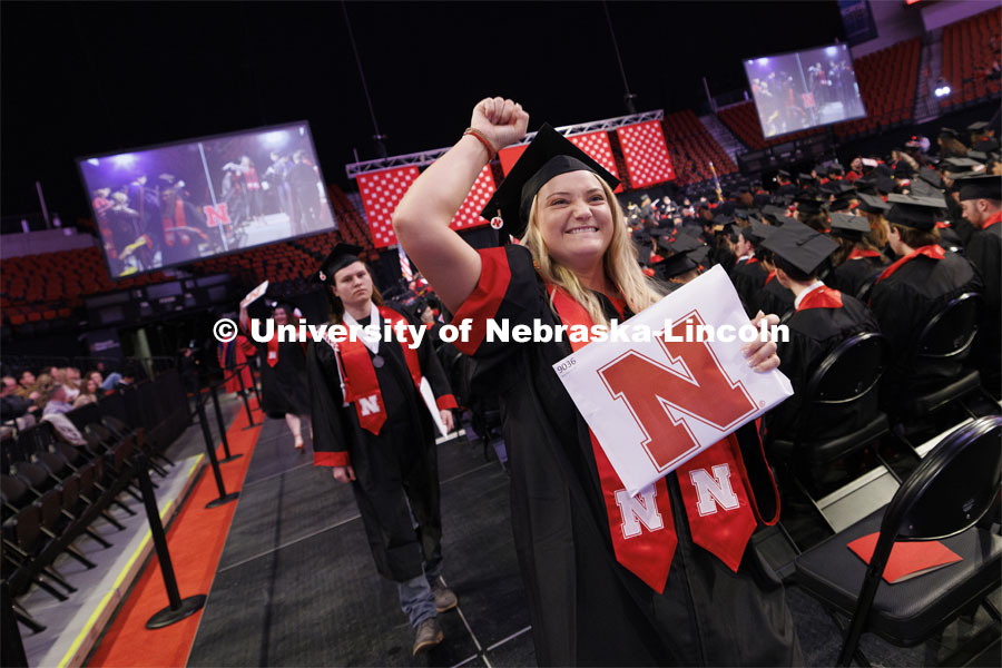 Megan Fehr fist pumps the air as she shows her communication studies diploma to family and friends. Winter undergraduate commencement in Pinnacle Bank Arena. December 16, 2023. Photo by Craig Chandler / University Communication and Marketing.