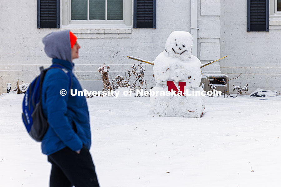Only the snowmen were smiling Tuesday as Cale Gowen, a junior from Hastings, walks past a smiler outside the Phi Kappa Psi fraternity house. Snow on city campus. January 9, 2024. Photo by Craig Chandler / University Communication and Marketing.