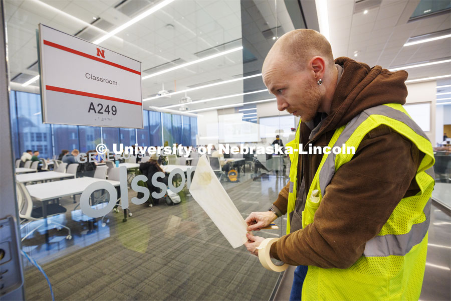 Caleb Dutton of Nebraska Sign applies the signage to a second-floor classroom. The classrooms were equipped through donations. The equipment and technology for this classroom was donated by Olsson Engineering. First day of classes in Kiewit Hall. January 22, 2024. Photo by Craig Chandler / University Communication and Marketing.