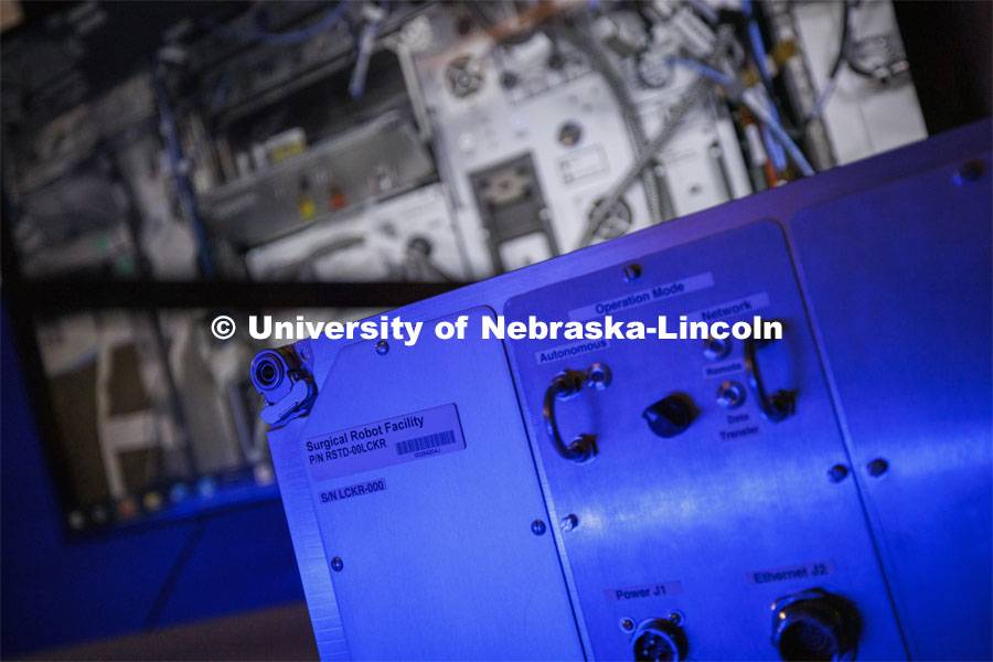 A duplicate of the box holding a Space MIRA sits on a table in front of screens showing the video feed from the International Space Station. Nebraska Engineering professor and Virtual Incision founder Shane Farritor successfully performed robotic surgery on the International Space Station. Controlled from the Virtual Incision offices in Lincoln, NE, surgeons cut rubber bands–mimicking surgery–inside a payload box on the International Space Station. February 10, 2024. Photo by Craig Chandler / University Communication and Marketing.