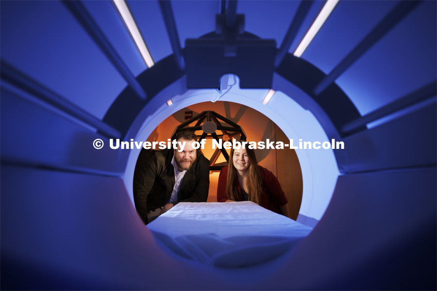 Douglas Schultz (left) and Heather Bouchard peer into the chamber of an MRI machine at the Center for Brain, Biology and Behavior, located within Memorial Stadium. Both from the Department of Psychology and members of CB3 are studying concussions. By working with athletes who recently experienced concussions, the team found that the connections among certain brain regions strengthened even as others weakened — and that these changes correlated with symptoms that often accompany concussions. The findings could help clarify how brain networks respond and reorganize following a concussion. February 21, 2024. Photo by Craig Chandler / University Communication and Marketing.