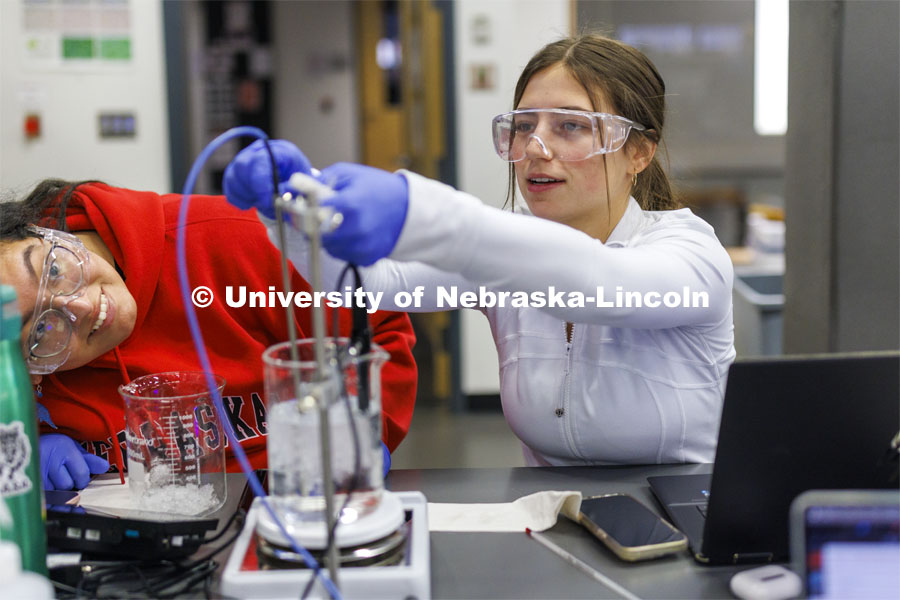 Grace Henry adjusts the heating and temperature probes in a sample fluid while lab partner Mayra Guerrero looks on. LIFE 120L - Fundamentals of Biology lab in Manter Hall. February 22, 2024. Photo by Craig Chandler / University Communication and Marketing.