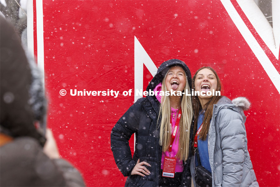 Ava Schmaderer and Makenna Lichty, both of Bennington, Nebraska, try to catch snowflakes on their tongues while being photographed in front of the inflatable N outside the Nebraska Union. Admitted Student Day is UNL’s in-person, on-campus event for all admitted students. March 23, 2024. Photo by Craig Chandler / University Communication and Marketing.