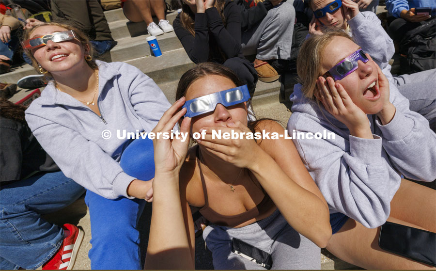Emma Jonas and Annie Masek react with the other Kappa Kappa Gamma members at 1:53 pm for the highest coverage of the sun. The Solar Social party to view the partial solar eclipse filled the greenspace outside the Nebraska Union on City Campus. April 8, 2024. Photo by Craig Chandler / University Communication and Marketing.