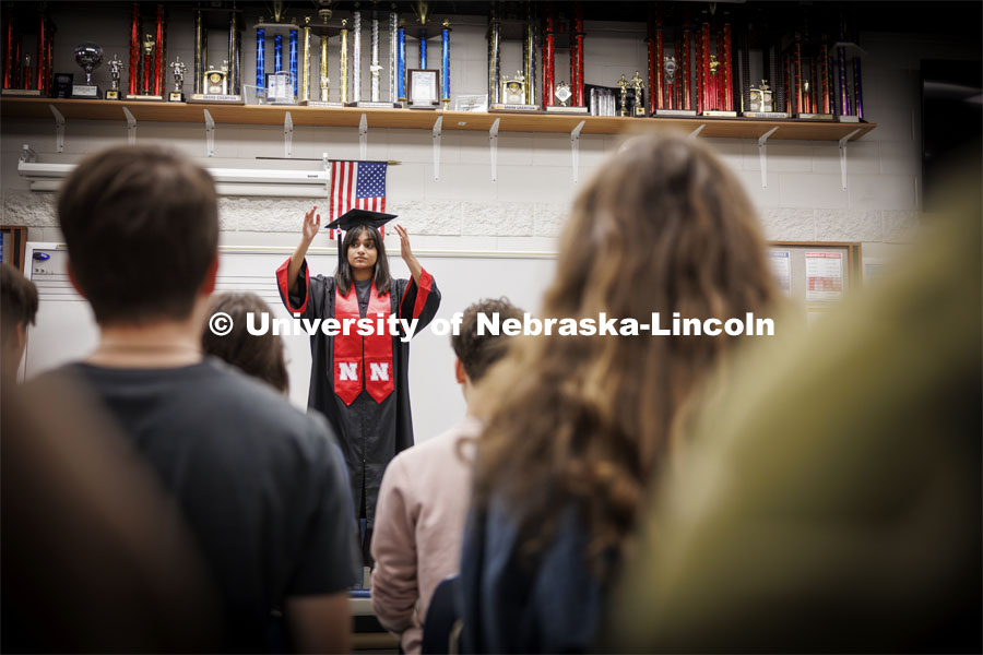 Ananya Amarnath, a May 2024 music education graduate, conducts the Papillion-La Vista South choir as they prepare for their spring performances. Amarnath is shown conducting in her graduation regalia. April 30, 2024. Photo by Craig Chandler / University Communication and Marketing.