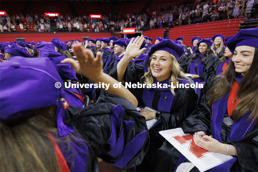 Emma Schlenker high fives her friend Jordyn Piper after they had received their hoods. College of Law commencement in Devaney on the volleyball court. May 3, 2024. Photo by Craig Chandler / University Communication and Marketing.