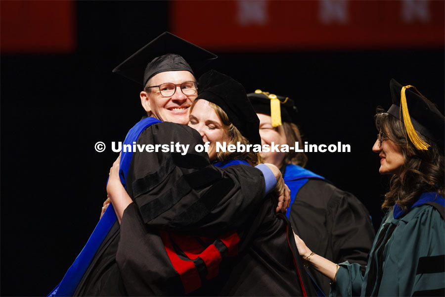 Johannah Rae Bashford-Largo hugs her dad, Professor Greg Bashford, after she received her psychology degree. At right is Maital Neta, her advising professor. Graduate Commencement. May 17, 2024. Photo by Craig Chandler / University Communication and Marketing.