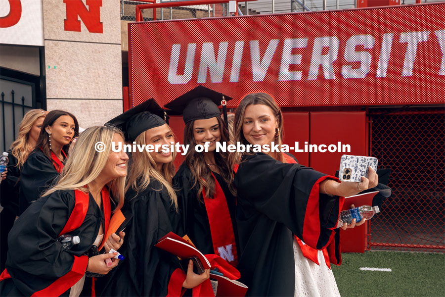 Liliana Zoellner, Hannah DeLashmutt, Emma Richards and Sara Knips snap a selfie at commencement. Undergraduate Commencement in Memorial Stadium. May 18, 2024. Photo by Kristen Labadie / University Communication.