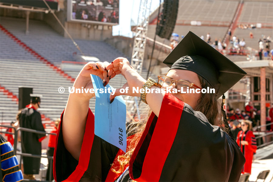 Maggie Nielsen, a Global Studies and Advertising Public Relations double major, holds up a heart to friends in the crowd. Undergraduate Commencement in Memorial Stadium. May 18, 2024. Photo by Kristen Labadie / University Communication.