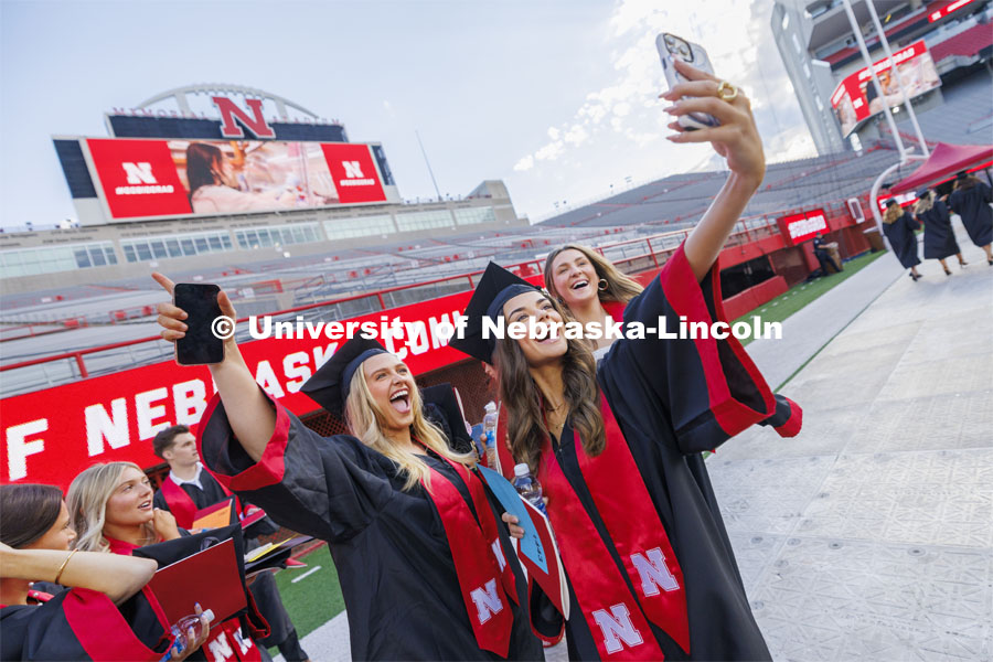 Hannah DeLashmutt, Emma Richards and Sara Knips record a video as they enter the field for commencement. Undergraduate Commencement in Memorial Stadium. May 18, 2024. Photo by Craig Chandler / University Communication and Marketing.