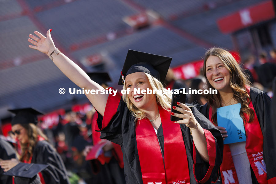Abby Newlun waves to get her family’s attention before commencement. Undergraduate Commencement in Memorial Stadium. May 18, 2024. Photo by Craig Chandler / University Communication and Marketing.