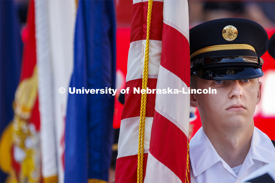 The ROTC cadet stands at attention near the flags. Undergraduate Commencement in Memorial Stadium. May 18, 2024. Photo by Craig Chandler / University Communication and Marketing.