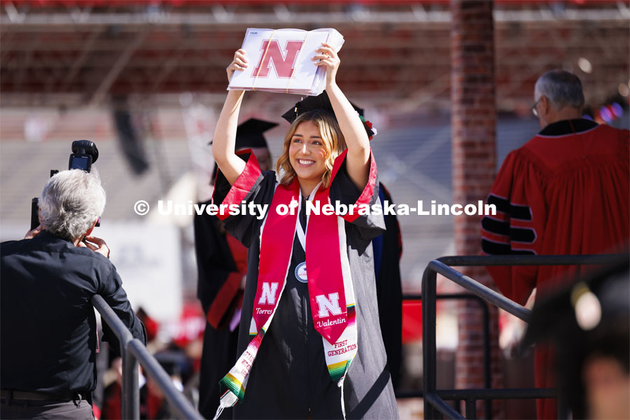 Monzeratt Valentin, a graduate with degrees in Global Studies, Political Science and Marketing, shows off her 3 diplomas to family and friends. Undergraduate Commencement in Memorial Stadium. May 18, 2024. Photo by Craig Chandler / University Communication and Marketing.