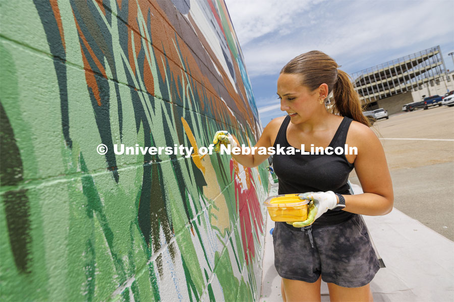 Maddie Vanderbur, a senior in graphic design and the mural’s designer, paints on the mural. ARTS 398 - Special Topics in Studio Art III taught by Sandra Williams. The class painted a mural at the Premier Buick, Chevrolet, and GMC dealership in Beatrice. June 3, 2024. Photo by Craig Chandler / University Communication and Marketing.