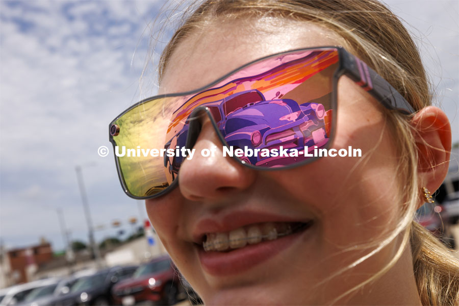 The mural is reflected in Beatrice High School student Addison Schafer’s sunglasses. ARTS 398 - Special Topics in Studio Art III taught by Sandra Williams. The class painted a mural at the Premier Buick, Chevrolet, and GMC dealership in Beatrice. June 3, 2024. Photo by Craig Chandler / University Communication and Marketing.