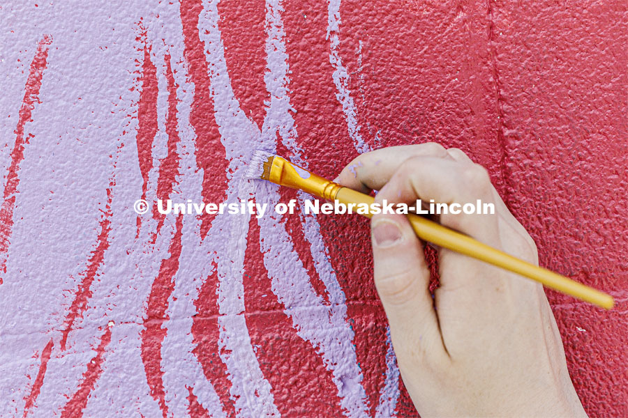 Lavender stripes are added to a flower petal on the mural. ARTS 398 - Special Topics in Studio Art III taught by Sandra Williams. The class painted a mural at the Premier Buick, Chevrolet, and GMC dealership in Beatrice. June 3, 2024. Photo by Craig Chandler / University Communication and Marketing.