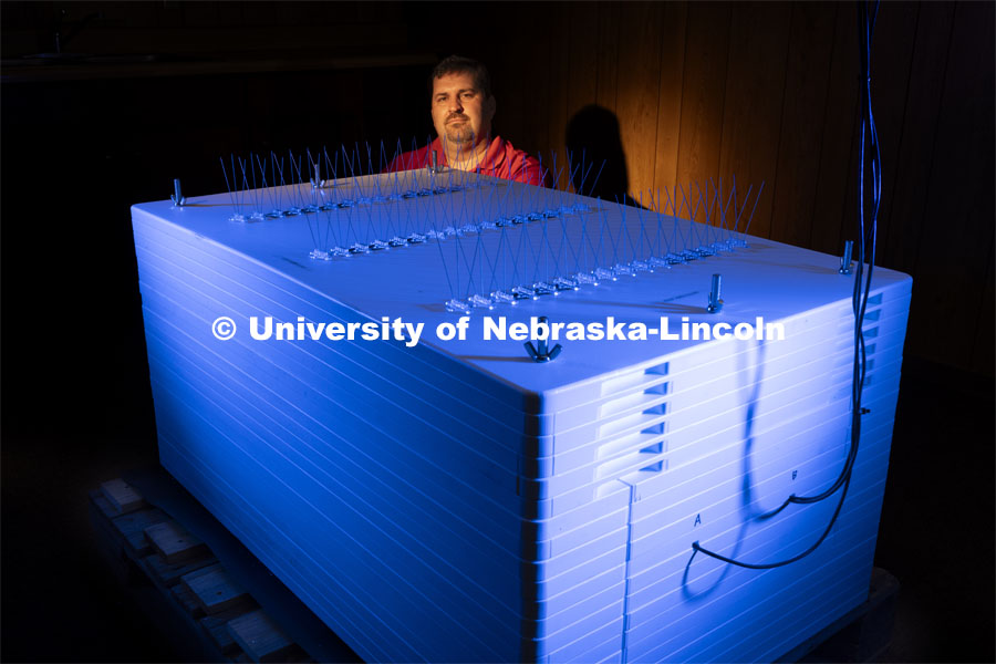 Trenton Franz, Professor of Hydrogeophysics at Nebraska, stands beside the newly installed neutron monitor, one of only three in the United States. The device, at UNL's Eastern Nebraska Research, Extension and Education Center near Mead, provides reliability to soil moisture readings collected by UNL and other institutions by removing distortions that cosmic rays introduce in the data. Funders for the device include the National Science Foundation and the U.S. Geological Survey. Franz is using neutron and cosmic ray detectors to see how solar radiation and solar energy such as those that caused Nebraska to view the Northern Lights is effecting precision farming including soil moisture detectors and the GPS in tractors. June 21, 2024. Photo by Craig Chandler / University Communication and Marketing.
