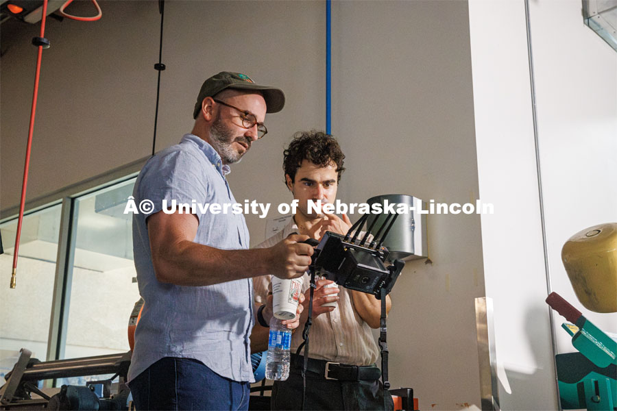 Aaron Nix and Matthew Strasburger look over camera angles while filming the Nebraska Innovation Studios welding robot. Behind the scenes photo for the university's new "Home Again" national advertisement. June 25, 2024. Photo by Kristen Labadie / University Communication.   