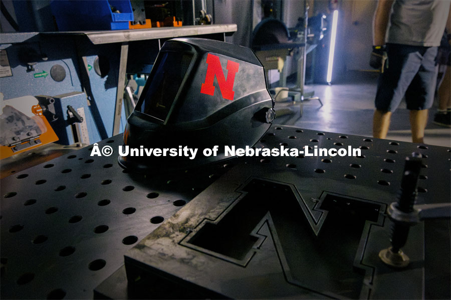 A welding helmet rests on the robotic welding table at Nebraska Innovation Studios. Behind the scenes photo for the university's new "Home Again" national advertisement. June 25, 2024. Photo by Kristen Labadie / University Communication.   