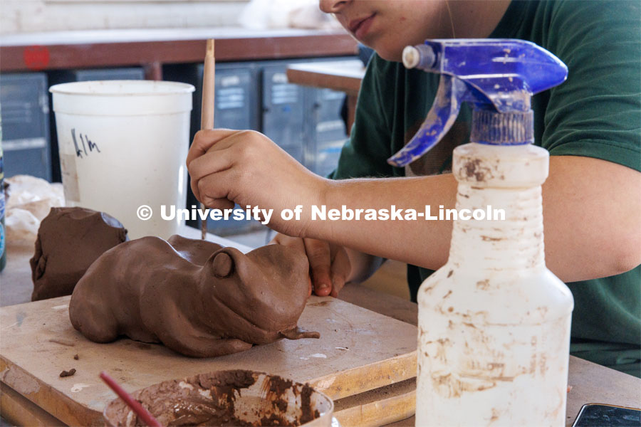 An art student molds her frog sculpture from clay. Behind the scenes photo for the university's new "Home Again" national advertisement. June 25, 2024. Photo by Kristen Labadie / University Communication.