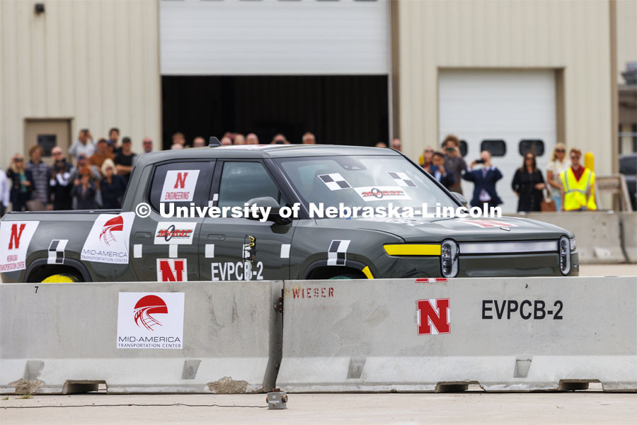 A gathered crowd of dignitaries watch as a Rivian R1T EV crashes into the barrier. In research sponsored by the U.S. Army Engineer Research and Development Center, the University of Nebraska-Lincoln’s Midwest Roadside Safety Facility is investigating the safety questions raised by the burgeoning number of electric vehicles on the nation’s roadways by performing crash test performed on a guardrail at 62 mph, the 7,000-plus-pound, Rivian R1T truck crashed into a temporary barrier. The barrier deflected several feet but the truck did not go through the barrier. July 1, 2024. Photo by Craig Chandler / University Communication and Marketing.